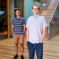 Two men standing in front of a staircase 